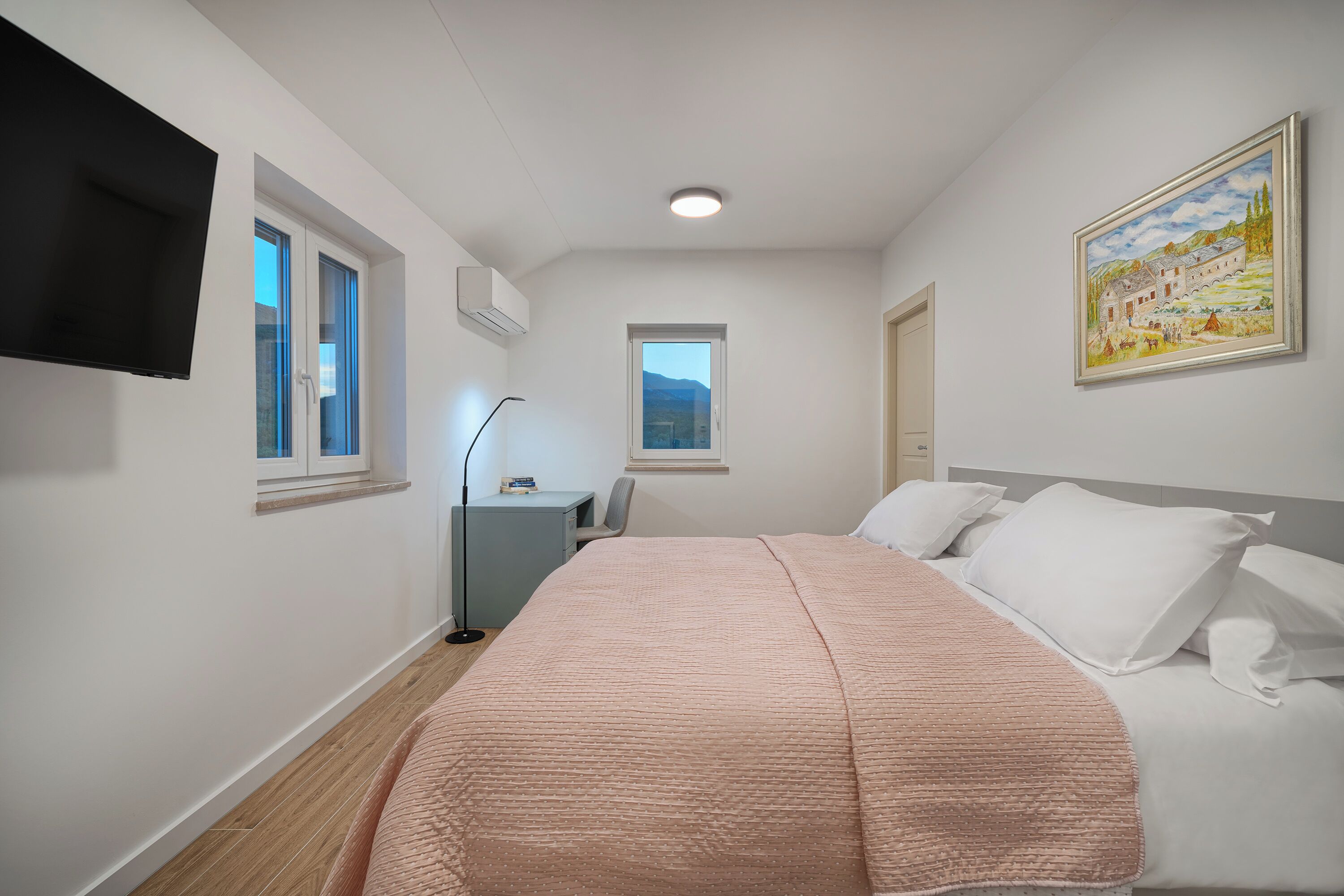 Un dormitorio con una cama, un escritorio, una silla y un televisor.