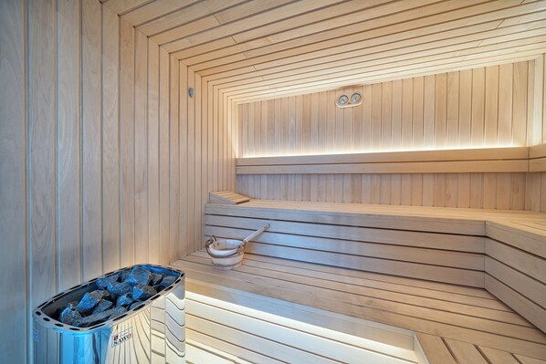 A sauna with wooden benches and a sloped floor design.