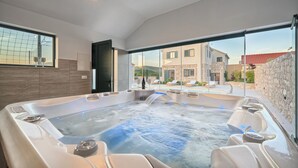 A modern spa area with a hot tub, seating, and a view of the surrounding buildings.