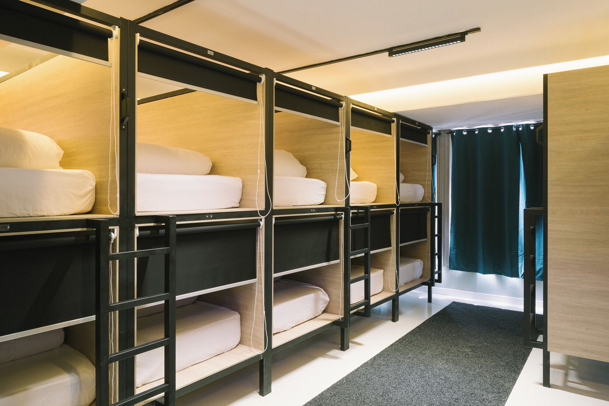 A room with bunk beds, a dark carpet, and a wooden wall.