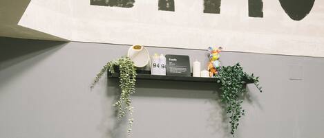 A small room with a table and two yellow chairs, a shelf with plants, and a sign with the word "DIVIDED" on the wall.
