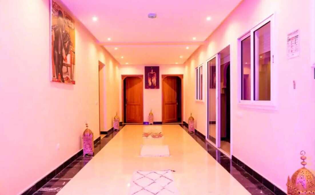 A hallway with a marble floor, wooden doors, and wall-mounted lights.