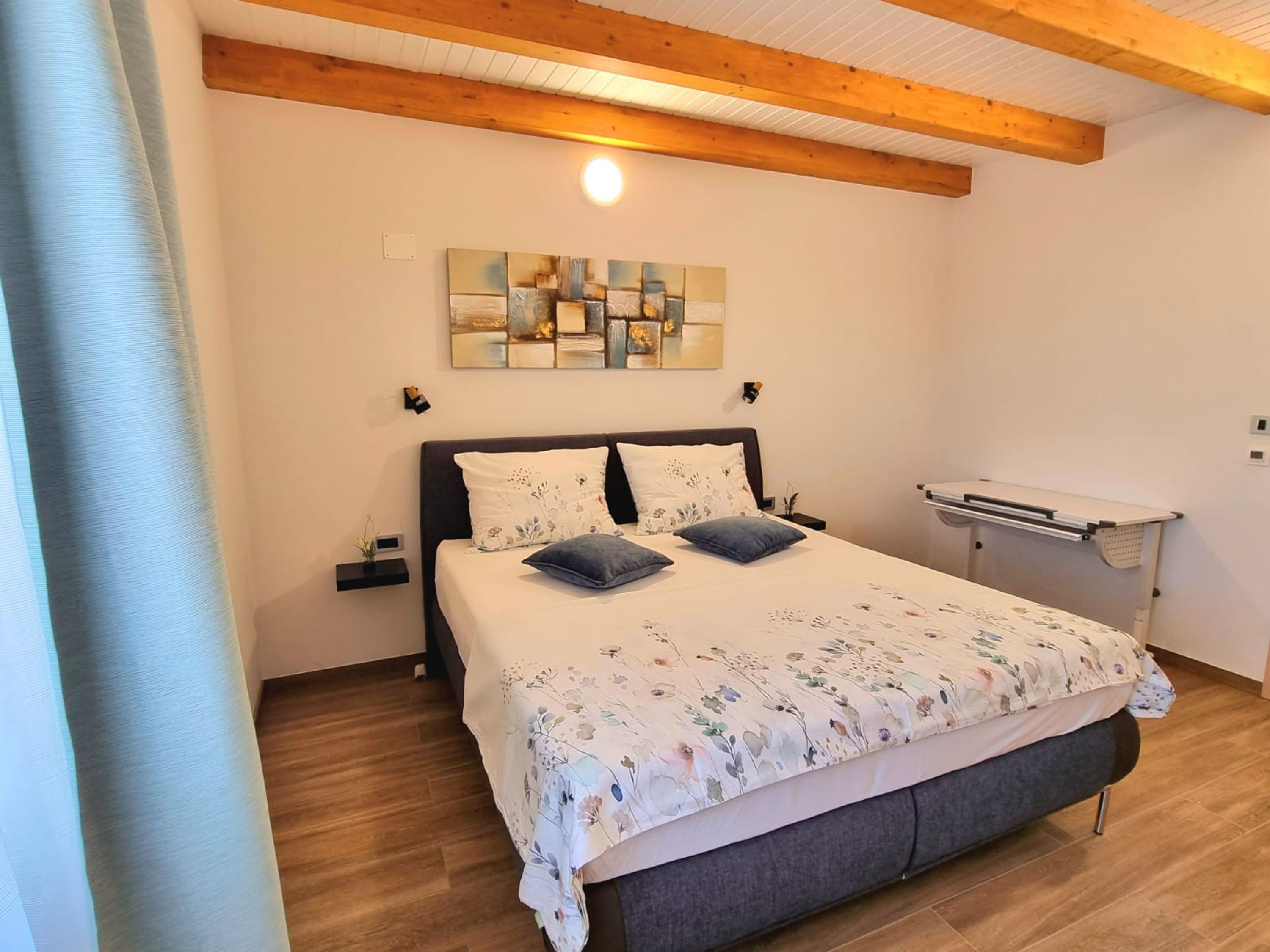 Une chambre à coucher comprenant un lit, une table de chevet, une étagère fixée au mur et un luminaire au plafond.