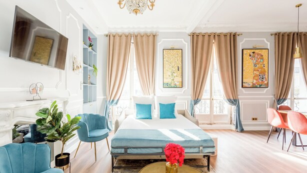 A hotel room with a bed, a TV, a chandelier, and a view of the city. - Merveil Luxury Suites - Septembre I-II (Paris)