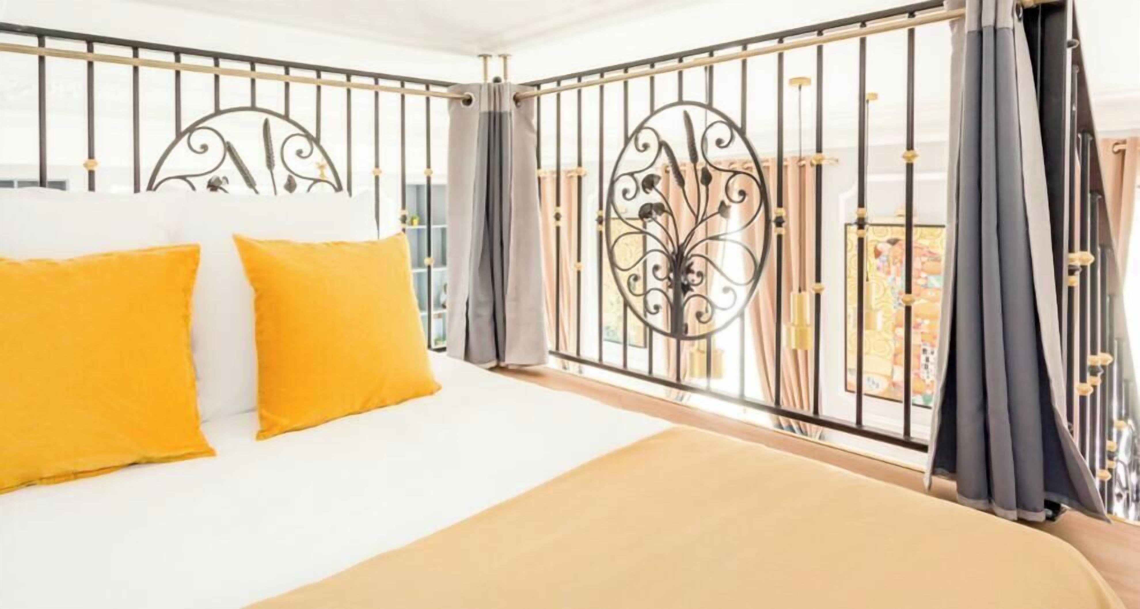 Ein Hotelzimmer mit Bett, Vorhängen und einem Balkongeländer.