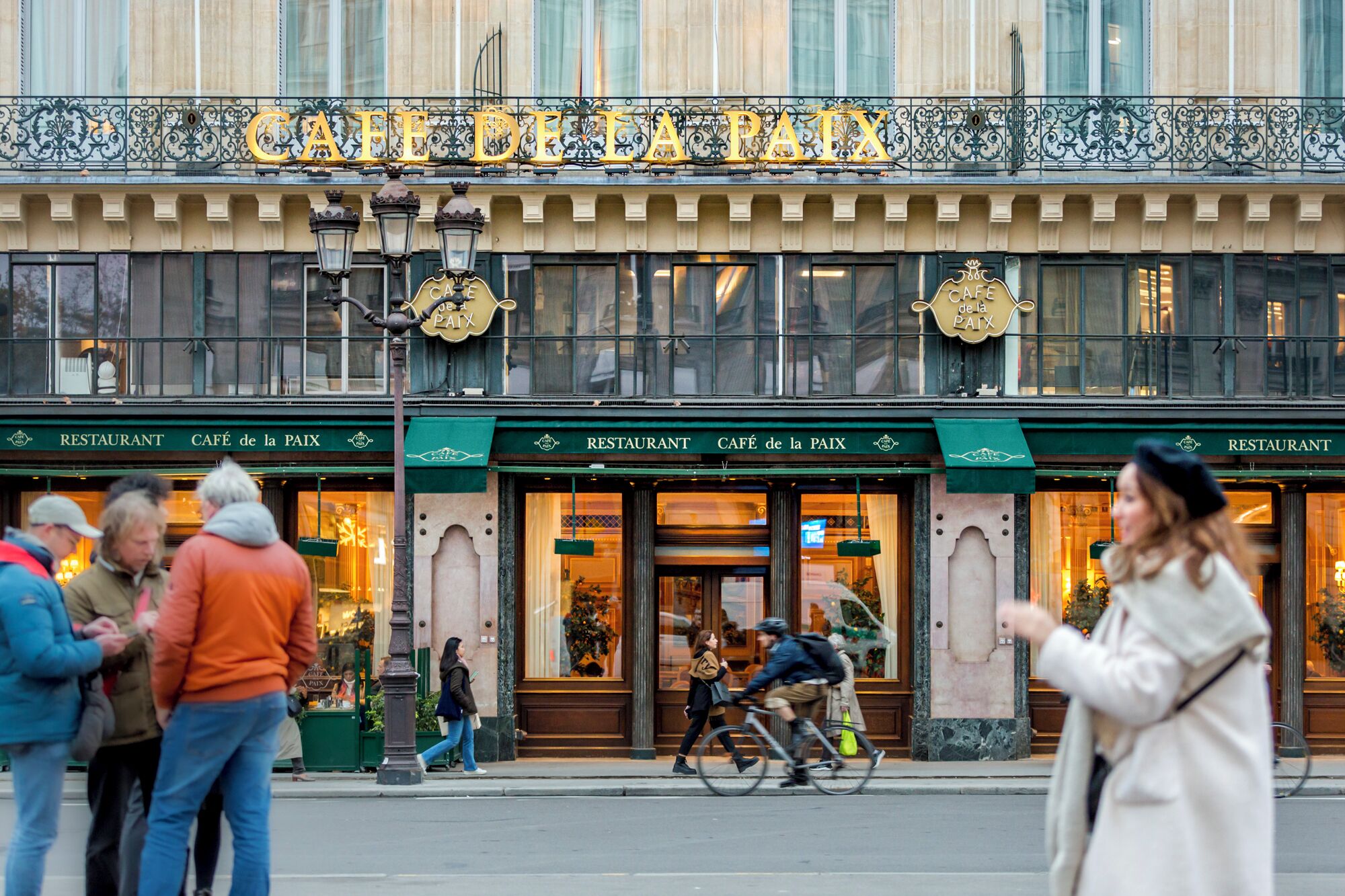 A building with a sign reading 'CAFÉ de la PAIX' and 'RESTAURANT' indicating a café and restaurant establishment.