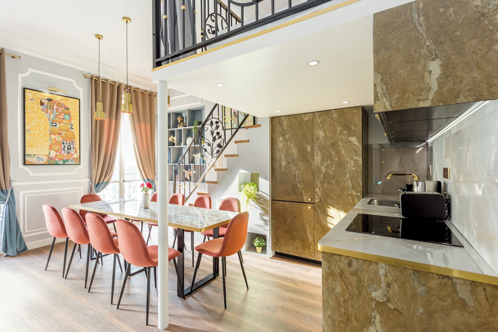 Une cuisine moderne avec un pare-feu en marbre, un coin repas doté d’une table en verre et un escalier agrémenté d’une rampe décorative.