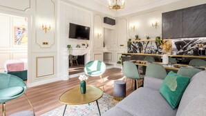 A modern living room with a fireplace, a television, and a dining area with a marble countertop. - Merveil Luxury Suites - Septembre I-II (Paris)