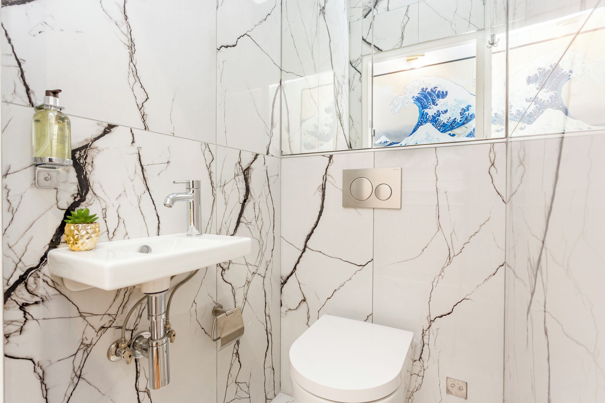 A bathroom with a white sink, a toilet, and a mirror with a decorative frame.