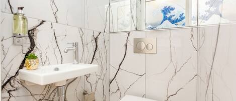A bathroom with a white sink, a toilet, and a mirror with a decorative frame.