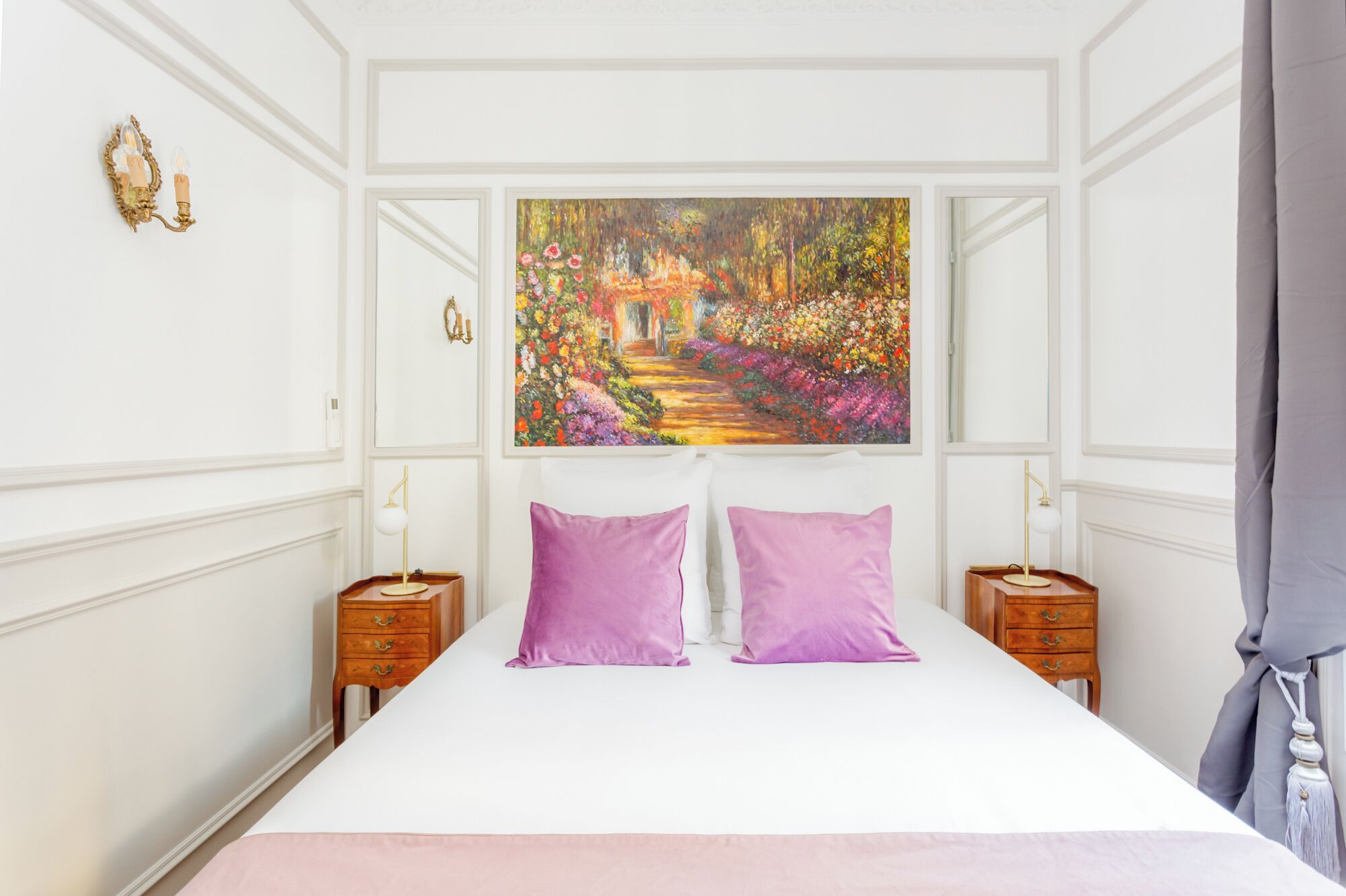 Una camera da letto con un letto grande, due comodini, un quadro sopra il letto e una finestra con tende.