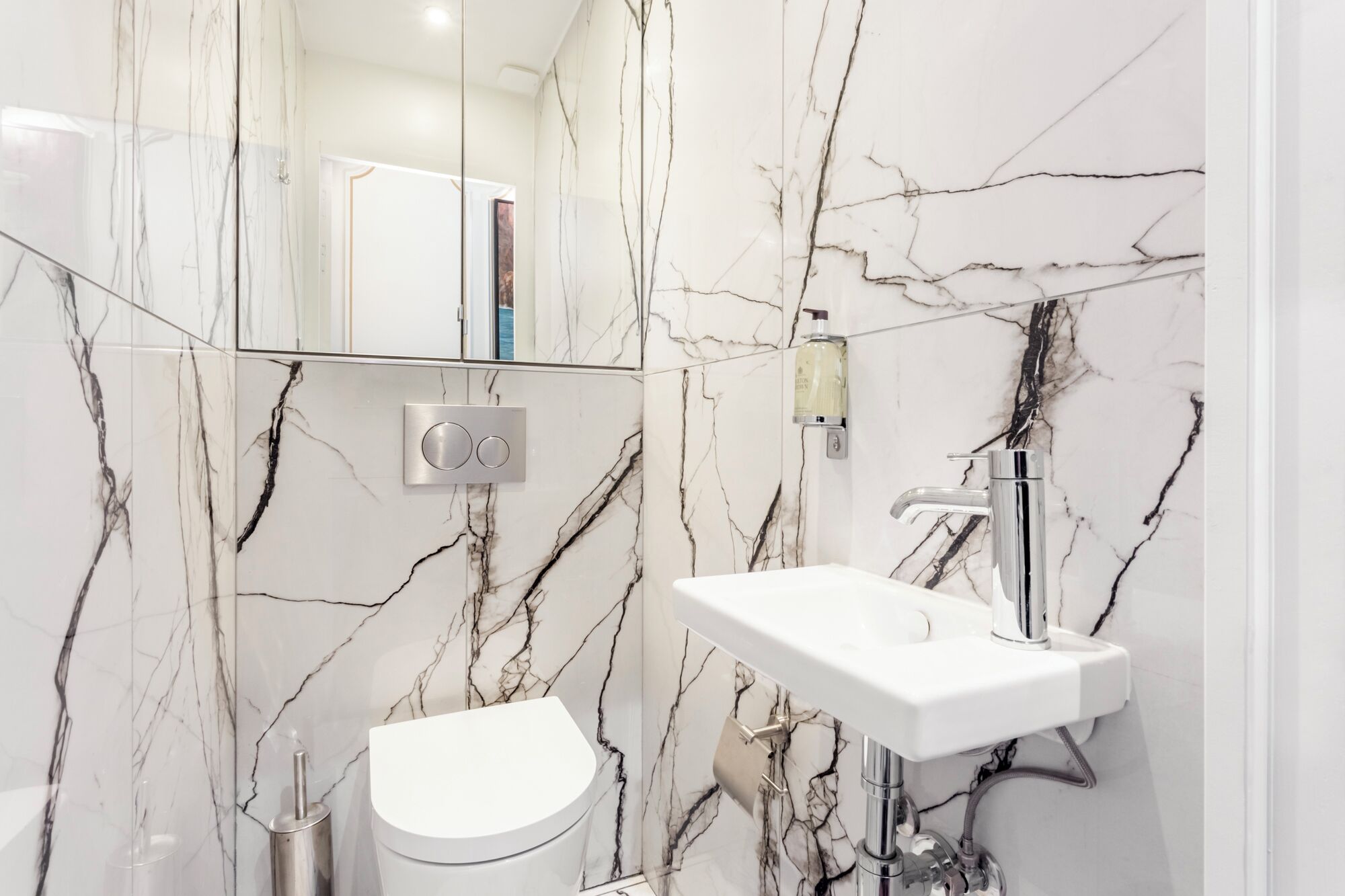 A bathroom with a white toilet, a sink, and a mirror.