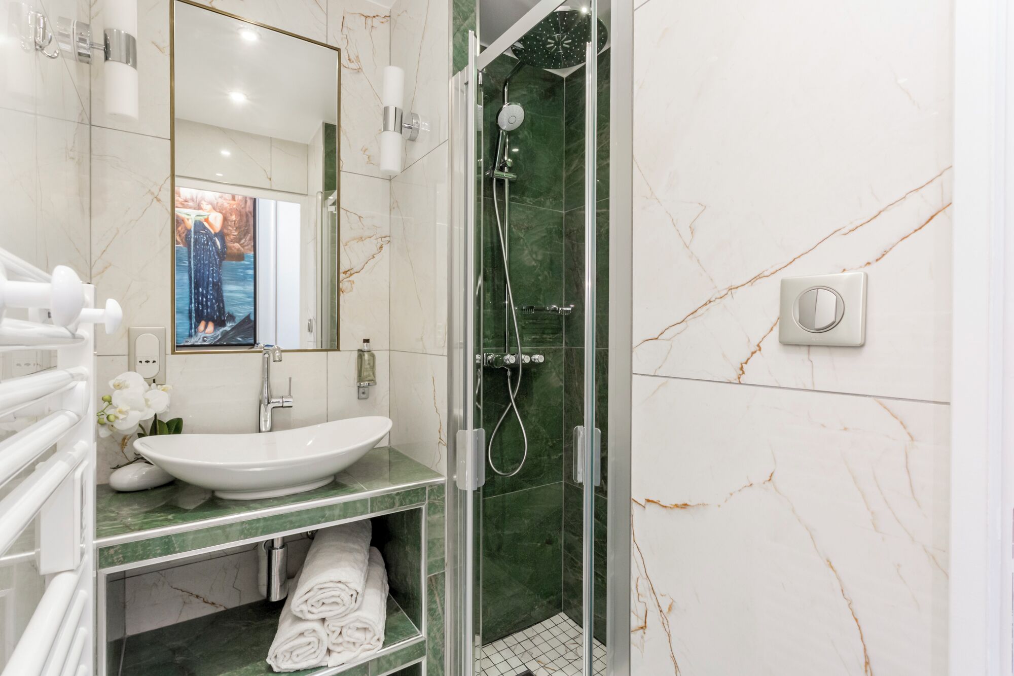 A modern bathroom with a glass-enclosed shower, a white sink, and a marble-tiled vanity.