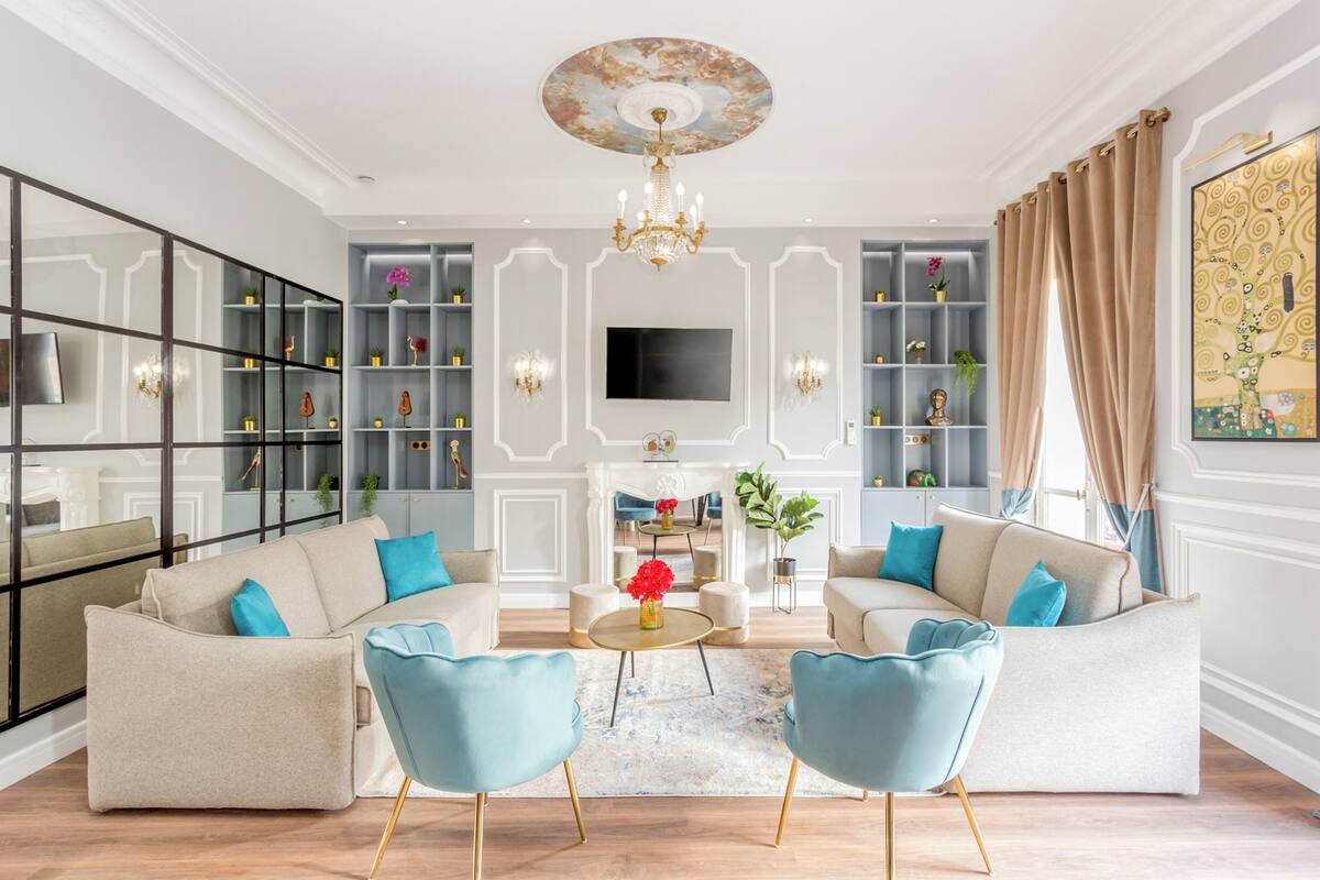 A modern living room with a sofa set, a chandelier, a TV, and built-in shelving.