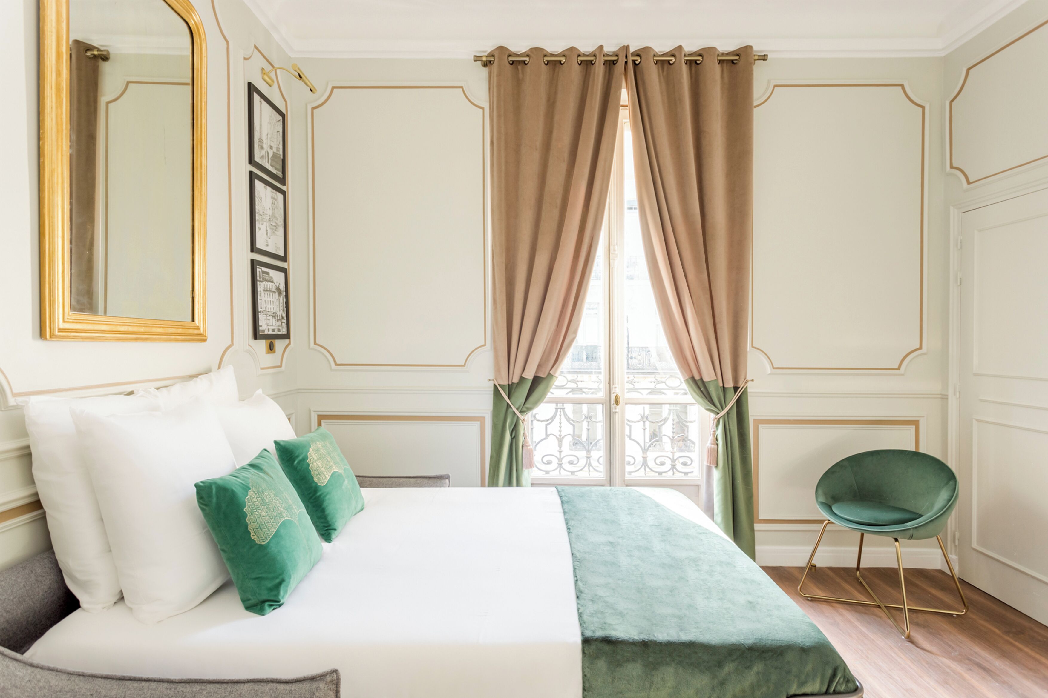 Ein Hotelzimmer mit einem Bett, grünen Kissen, einer grünen Tagesdecke, einem grünen Sessel und einem Fenster mit Vorhängen.