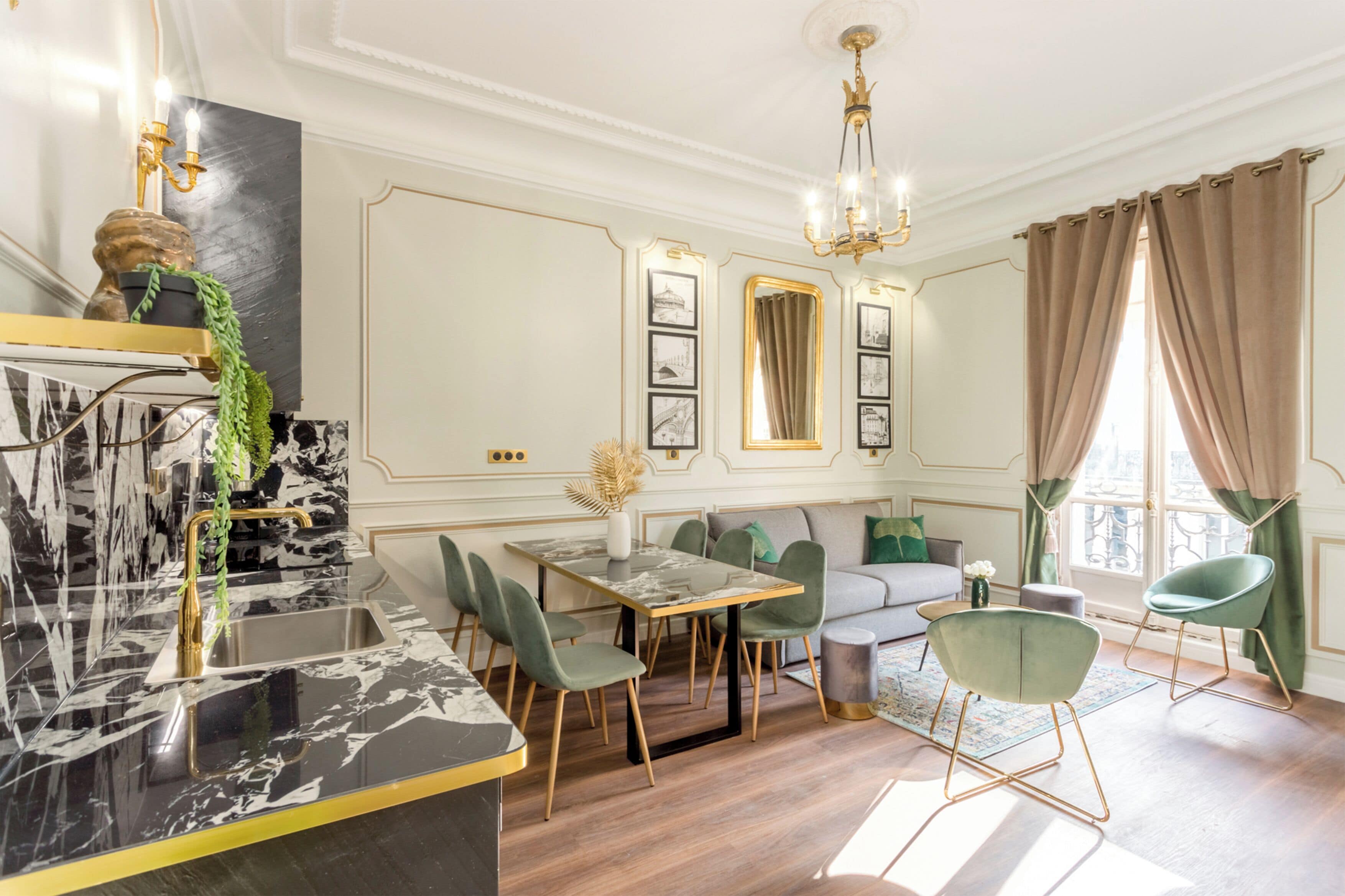 Un espace repas doté d’un comptoir en marbre, de chaises vertes, d’une table en bois et d’un lustre.