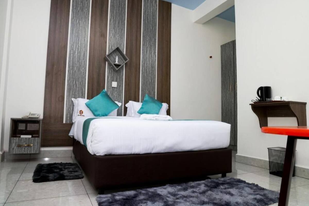 A modern bedroom with a large bed, a nightstand, a desk, and a chair.