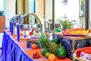 Uma mesa de buffet com diversas frutas e um dispensador de água.