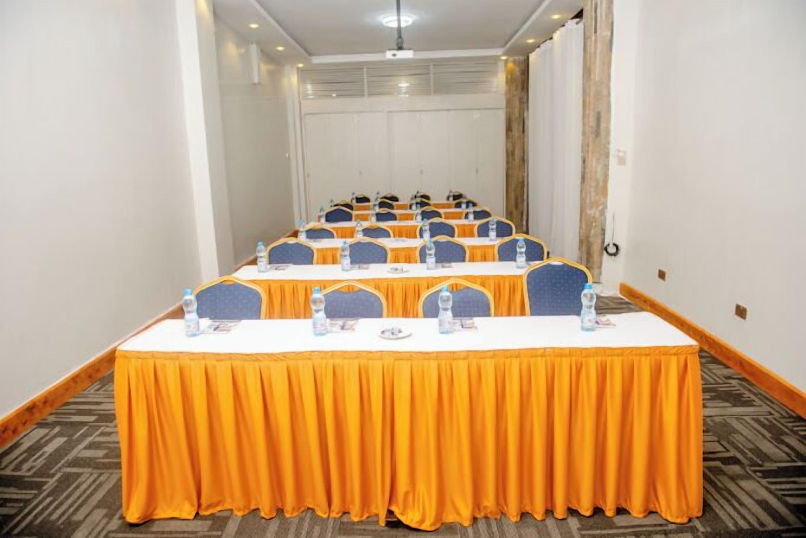 Une salle de conférence avec une longue table, des chaises et des bouteilles d’eau.