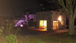 Un bâtiment en pierre avec une entrée illuminée et un petit jardin.