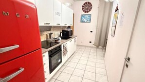 A compact kitchen with white cabinets, a red refrigerator, and a tiled floor. - Max- Fortuna ground floor apartment (Ragusa)