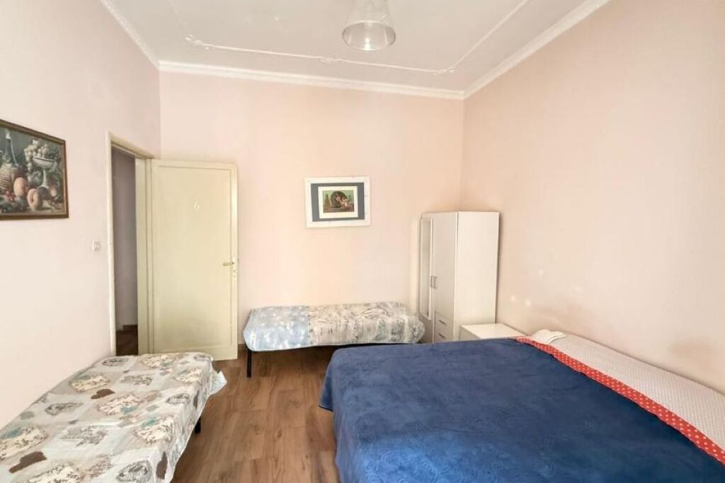 Ein Schlafzimmer mit zwei Betten, einem Kleiderschrank und einer Tür zu einem weiteren Raum.