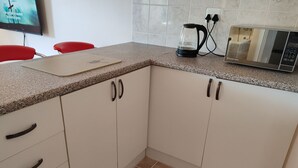 Una cocina con armarios blancos, encimera de granito, cafetera y microondas.