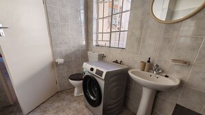 Un baño pequeño con lavadora, inodoro y lavamanos.