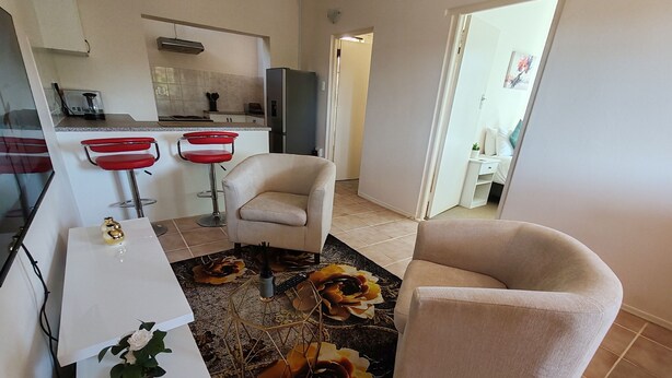 Una sala de estar moderna con un sofá, una mesa de comedor y una zona de cocina al fondo.