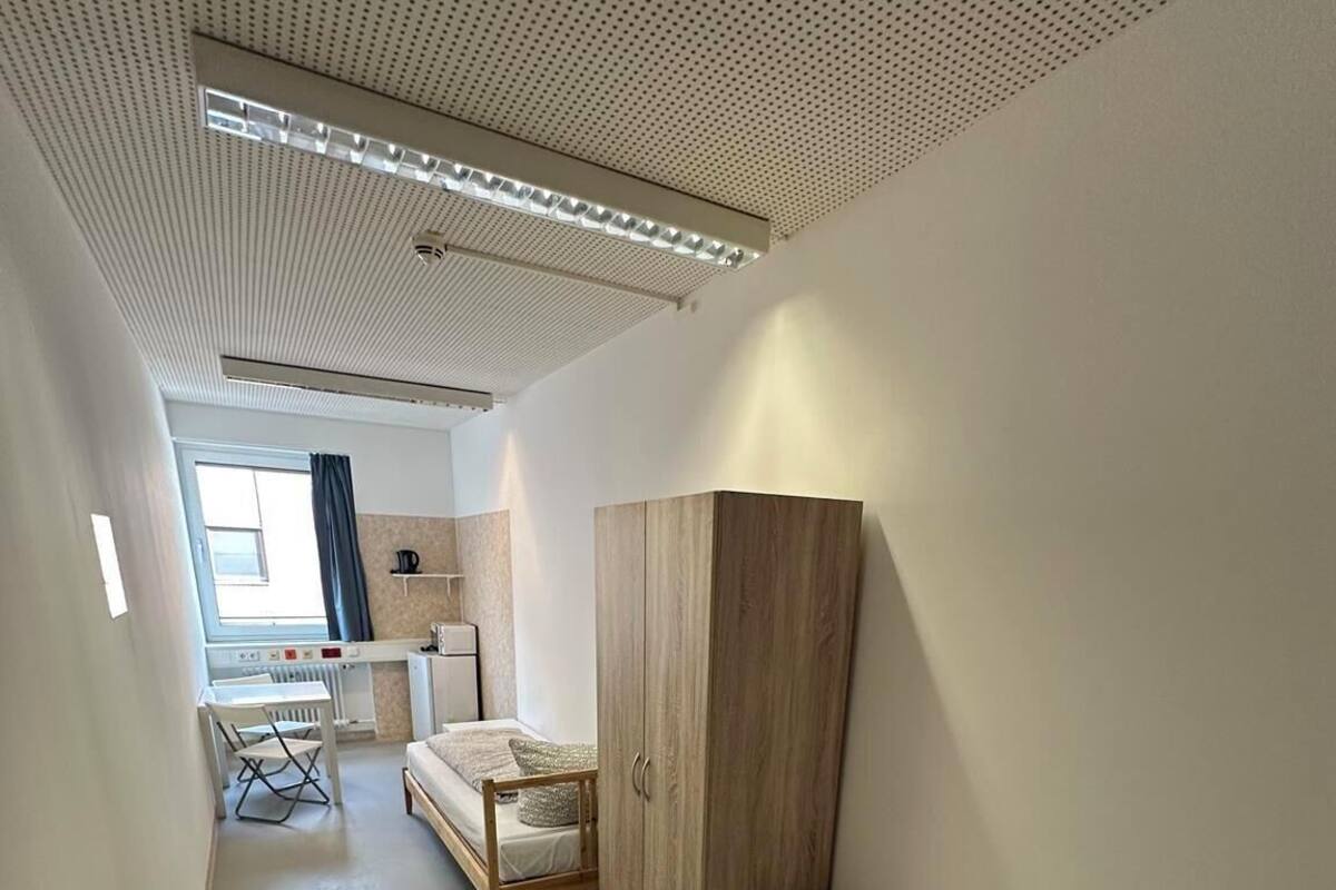 A compact, modern room with a bunk bed, a small desk, and a wardrobe.