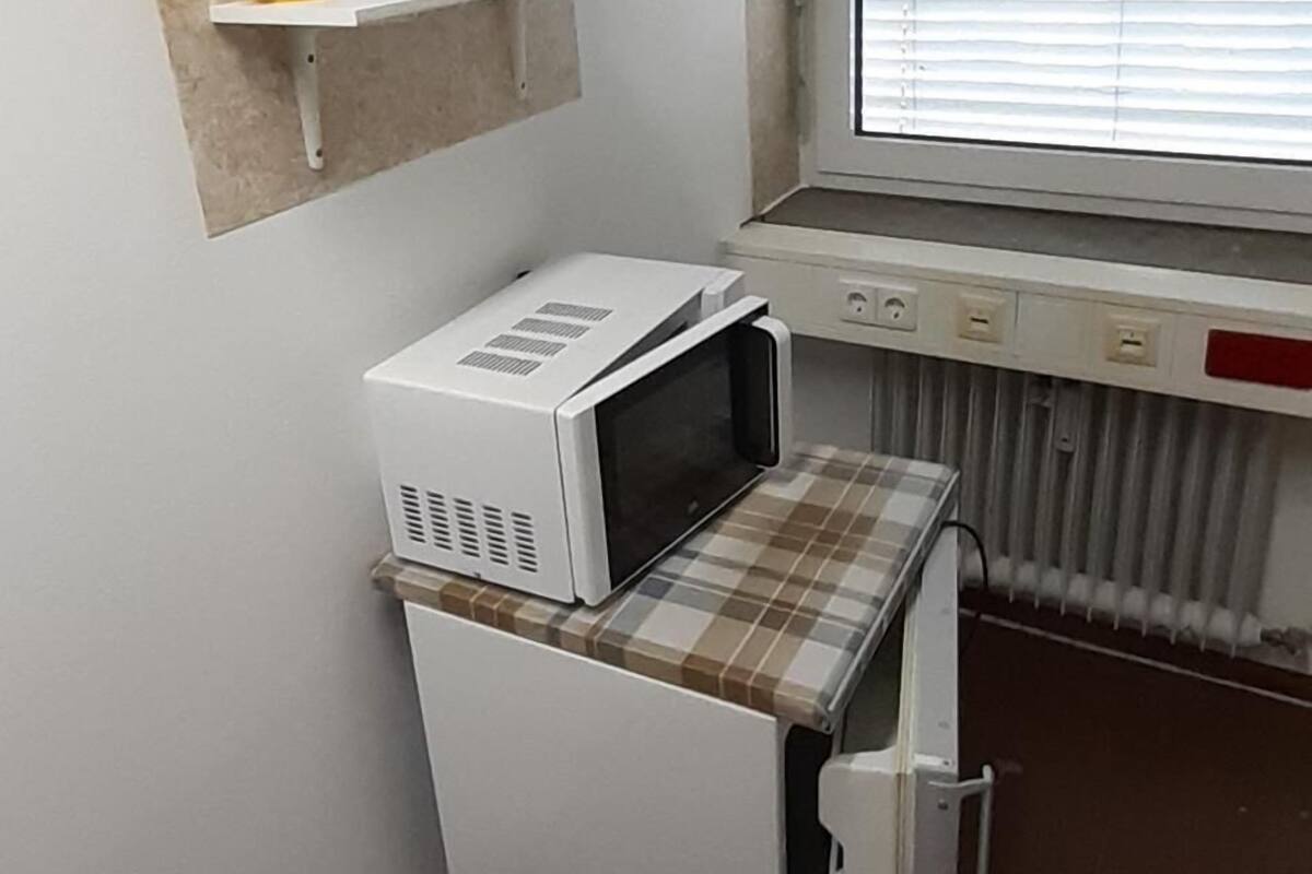 A compact kitchenette with a microwave, a small refrigerator, and a coffee maker on a shelf.