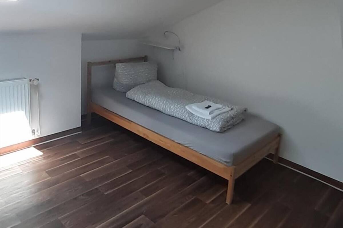 A small, sloped ceiling room with a single bed, wooden flooring, and a skylight.