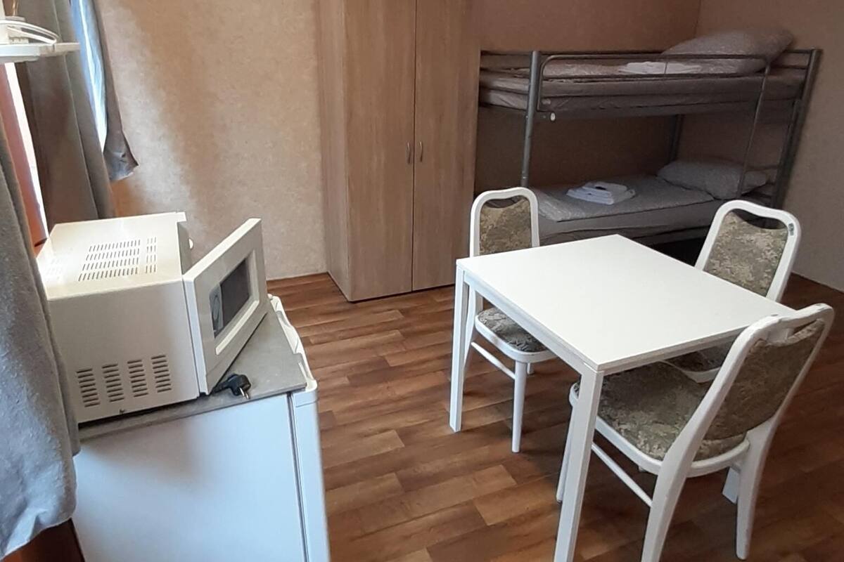 A compact room with a bunk bed, a small kitchenette, and a dining area with a table and chairs.