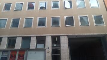 Un edificio de varios pisos con fachada color beige, varias ventanas y una entrada a nivel de calle con puerta.