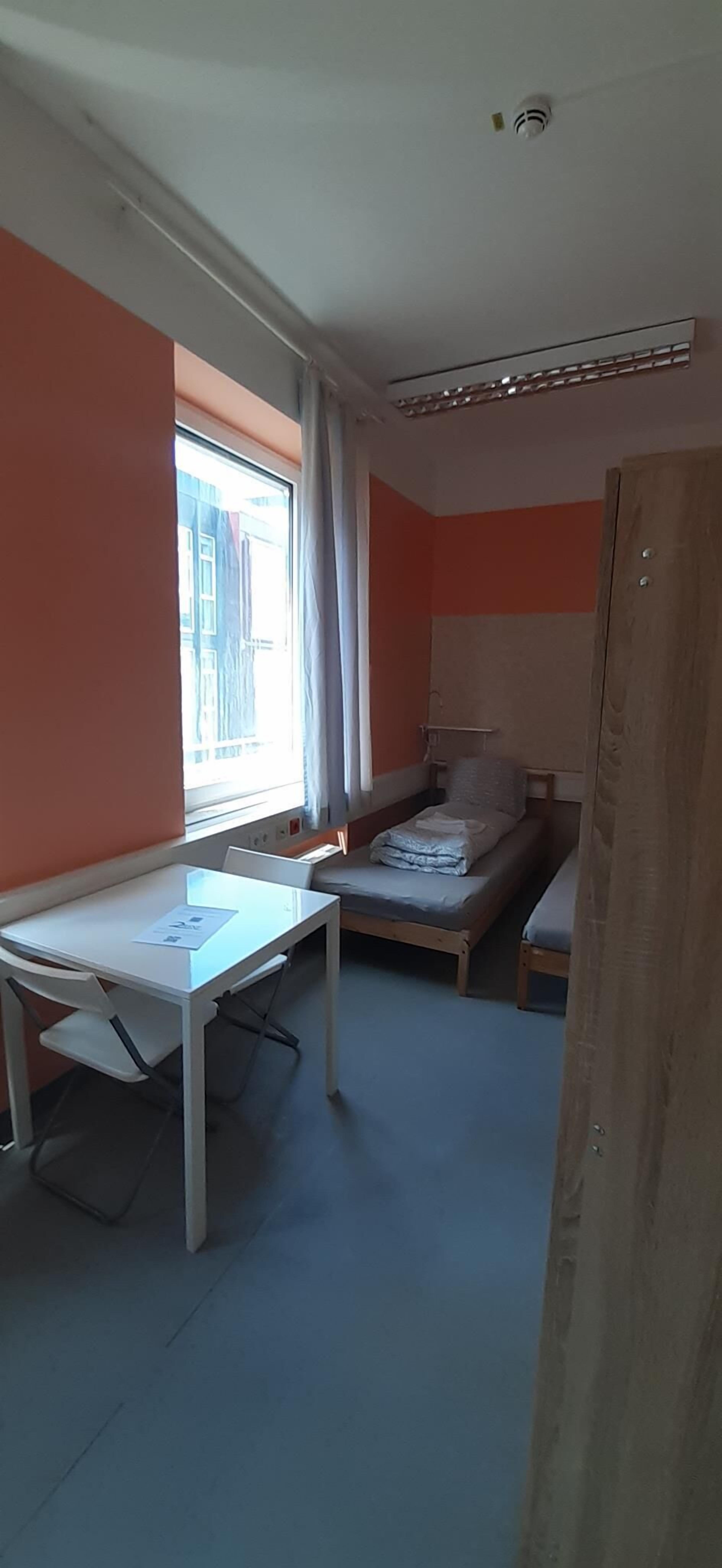 Huone, jossa on sänky, työpöytä ja ikkuna.