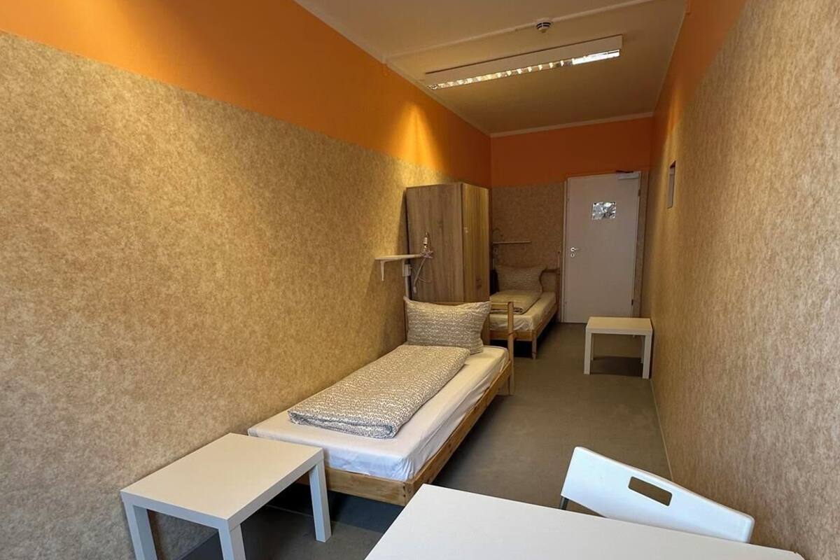 A compact room with a single bed, a small table, and a bench.