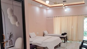 A modern hotel room with a large bed, a smaller bed, a seating area, and a bathroom. - Ocean Mist Beach Homestay (Bhatkal)