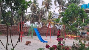 A playground with a blue slide, swings, and a sand area. - Ocean Mist Beach Homestay (Bhatkal)