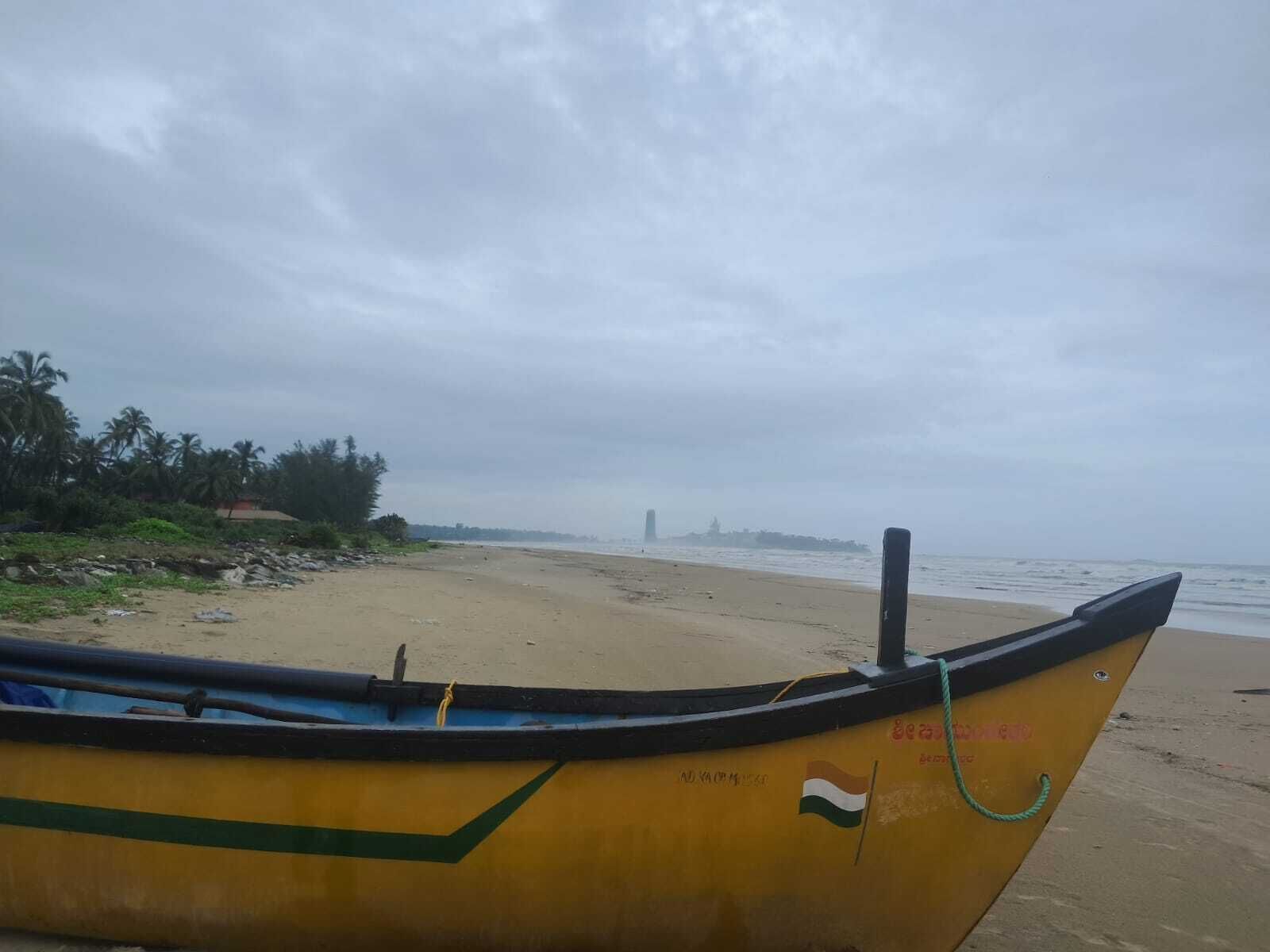 A boat on a beach with a cloudy sky.