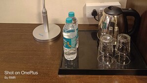 Una camera d'albergo con una scrivania, una lampada da scrivania, una bottiglia d'acqua e una macchina per il caffè.