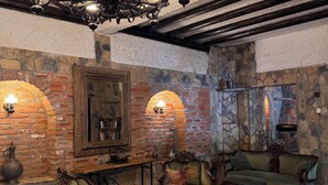 A rustic interior with exposed brick walls, a stone fireplace, and traditional wooden furniture. - Manastır Mandarin (Tahtakuslar)