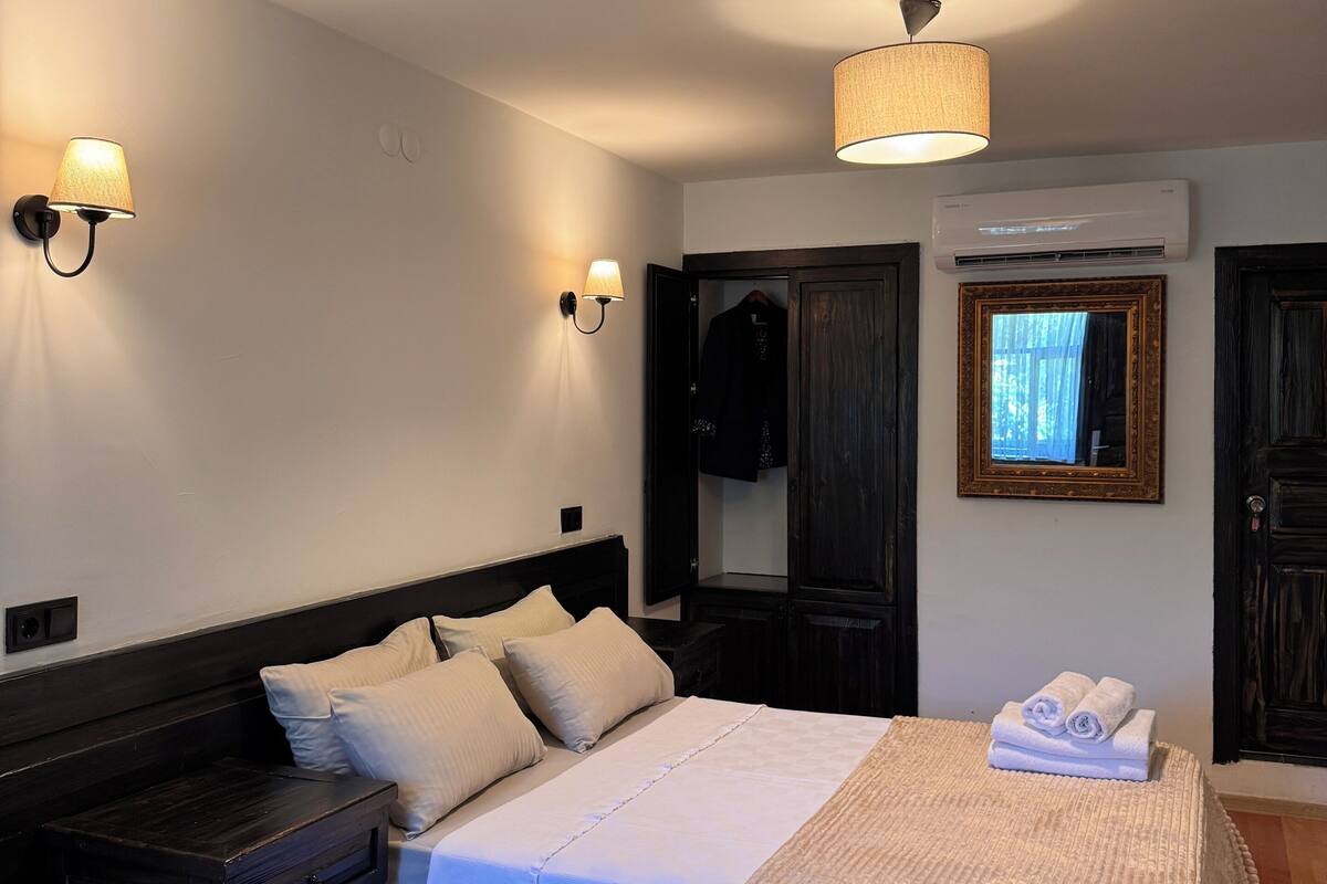 Un dormitorio con cama, mesitas de noche, armario y lámpara colgante.