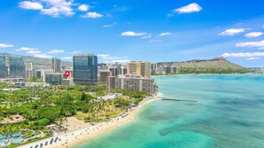 A coastal cityscape with a prominent hotel featuring a large red pin icon, indicating its location. - Heart of Waikiki, 2 blocks to beach, kitchenette, lanai, free parking nearby! (Honolulu)