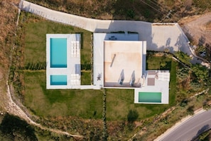 A large property with two swimming pools, a covered patio area, and a road adjacent to the property. - Luxury Villa in Crete with 3 Pools, Stunning Views & Total Privacy (Argiroupoli)