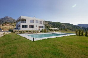 A modern two-story building with a swimming pool in front. - Luxury Villa in Crete with 3 Pools, Stunning Views & Total Privacy (Argiroupoli)