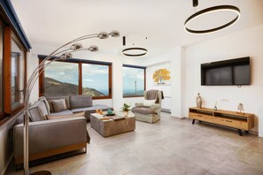 A modern living room with a sofa, armchair, coffee table, and a TV mounted on the wall.