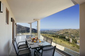 Varanda com mesa posta para dois, com vista para uma paisagem montanhosa.