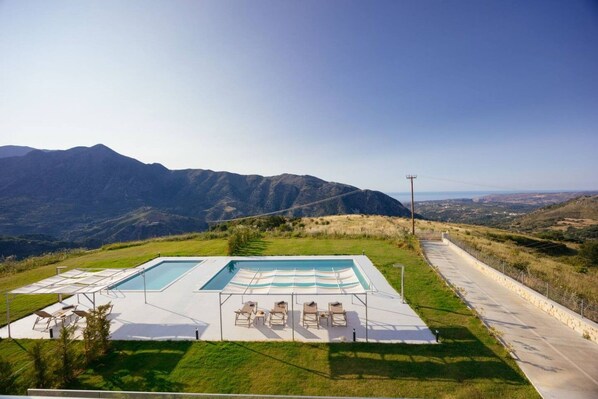 Piscina com espreguiçadeiras e vista para montanhas.