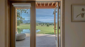Una habitación con piso de madera, un banco y vistas a un campo de golf y montañas.
