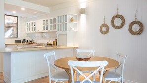 A modern kitchen with white cabinetry, a central island with seating, and decorative wall art. - Airlie Beach main street 2 minute walk (Airlie Beach)